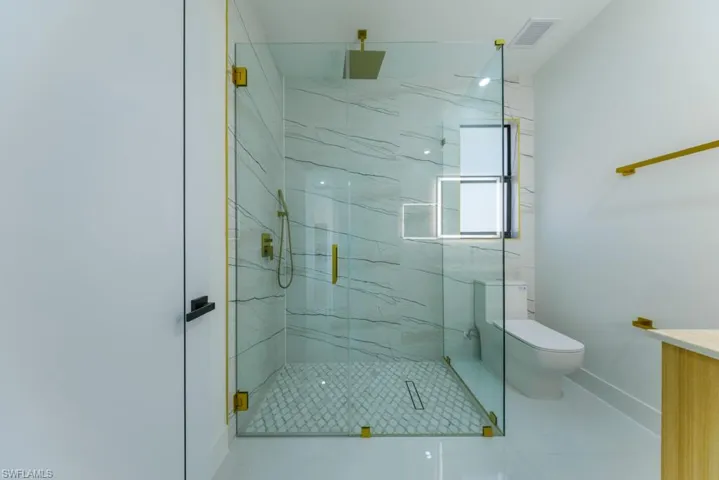 Bathroom featuring a marble finish shower, vanity, and tile patterned floors