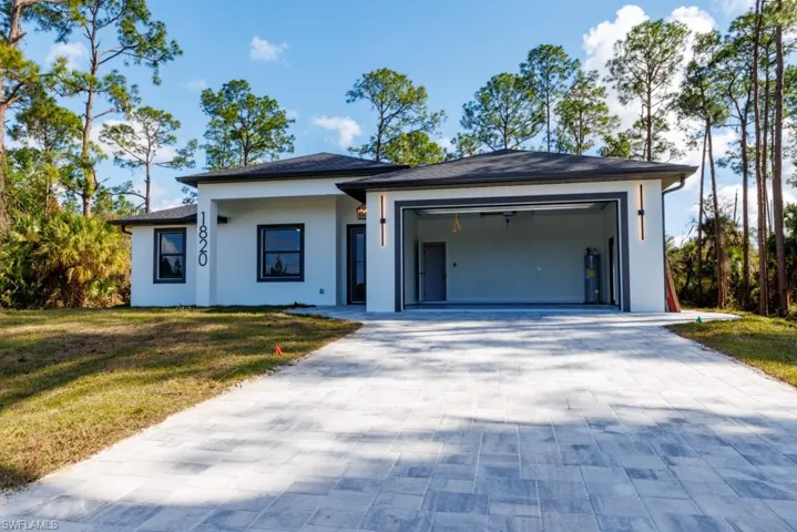 Prairie-style house with a front lawn, decorative driveway, stucco siding, and a garage