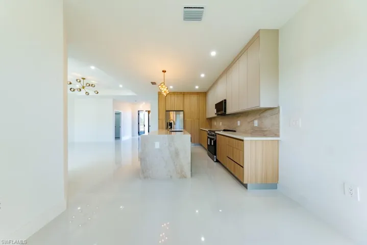 Kitchen featuring modern cabinets, appliances with stainless steel finishes, a chandelier, recessed lighting, and tasteful backsplash