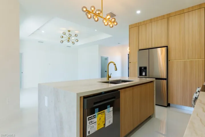 Kitchen with appliances with stainless steel finishes, hanging light fixtures, an island with sink, a chandelier, and modern cabinets