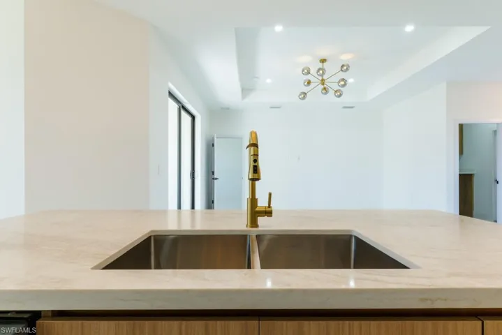 Kitchen with light stone counters, a chandelier, recessed lighting, and a raised ceiling
