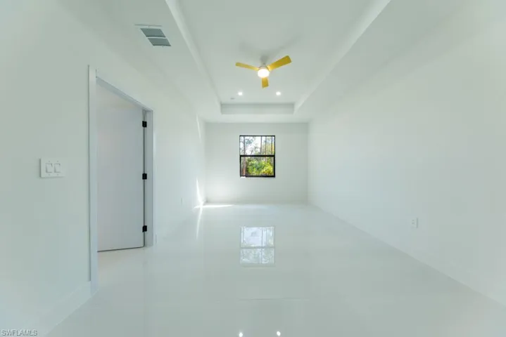 Empty room with a ceiling fan, a tray ceiling, and recessed lighting