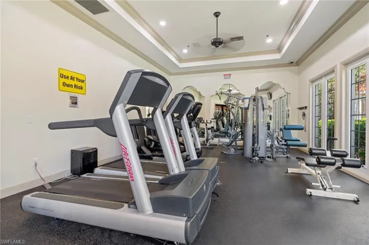Gym with ceiling fan, crown molding, a tray ceiling, and recessed lighting