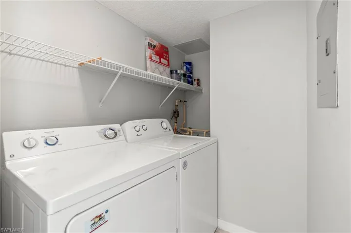 Laundry area featuring washer and clothes dryer, electric panel, and a textured ceiling