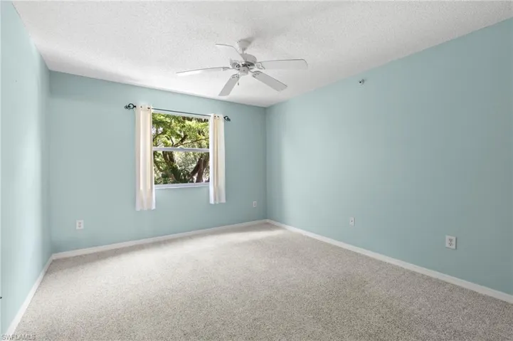 Carpeted empty room featuring a textured ceiling and ceiling fan