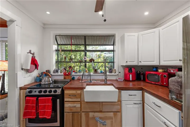 Kitchen featuring appliances with stainless steel finishes, white cabinetry, sink, light tile patterned floors, and ceiling fan