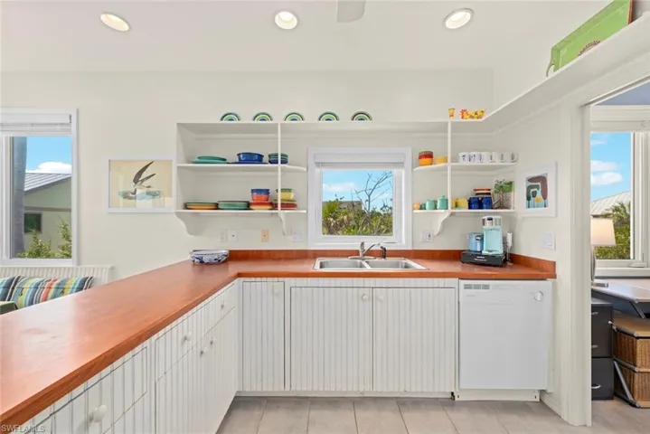Kitchen with hanging light fixtures, white cabinetry, a peninsula, open shelves, and light tile patterned flooring