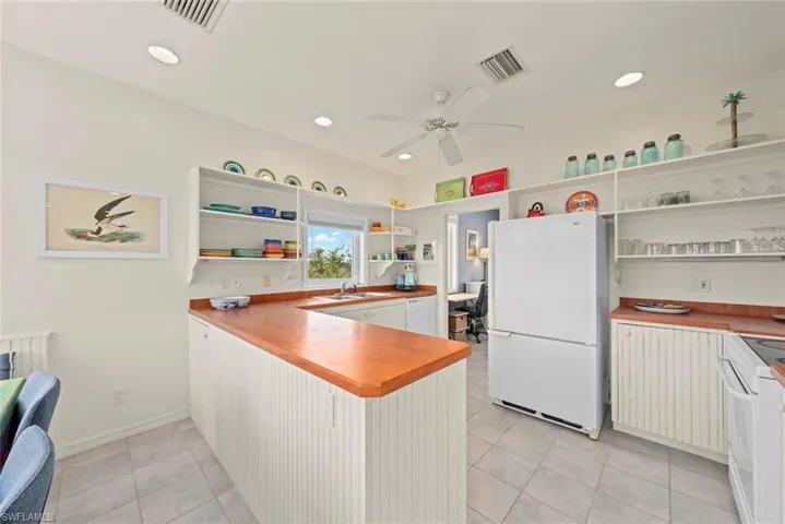 Kitchen with stainless steel appliances, open shelves, light tile patterned floors, recessed lighting, and white cabinetry
