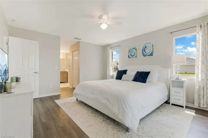 Spacious room featuring wood-finish flooring, multiple windows, a ceiling fan, and a light color palette