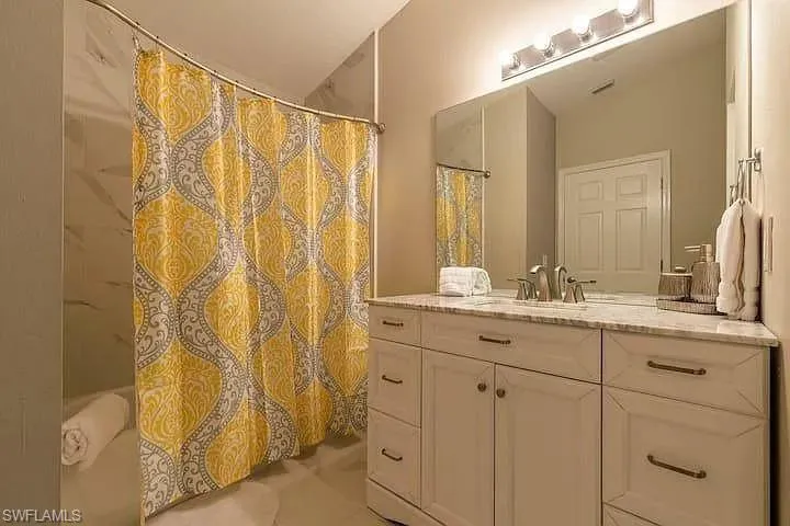 Spacious vanity with a light-toned countertop, dual under-mount sinks, and classic white cabinetry with bronze-finish hardware