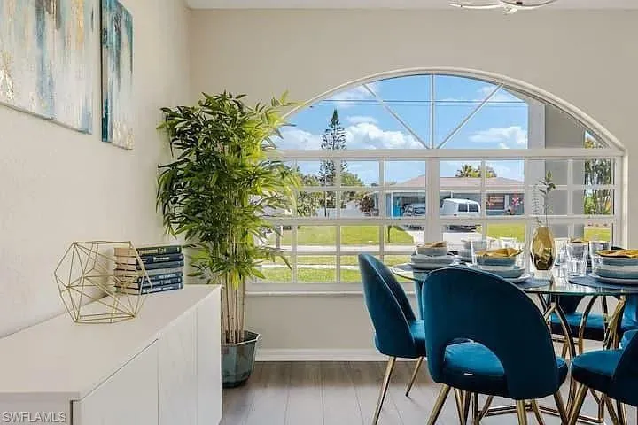 Arched window with gridded panes, dark wood-finish flooring, and white wall finishes