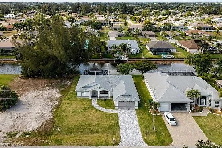 Property featuring a covered entry, attached garage, paver driveway, and manicured front lawn