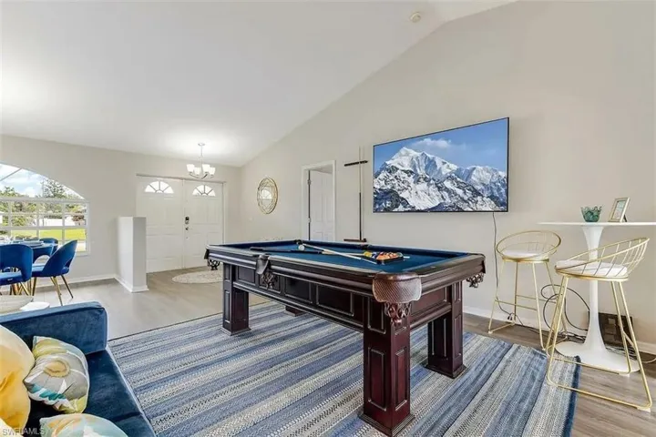 Vaulted ceiling, wood-finish flooring, arched window, double-door entry, and chandelier lighting