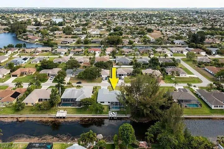Waterfront property featuring a private boat dock, screened pool enclosure, and mature landscaping