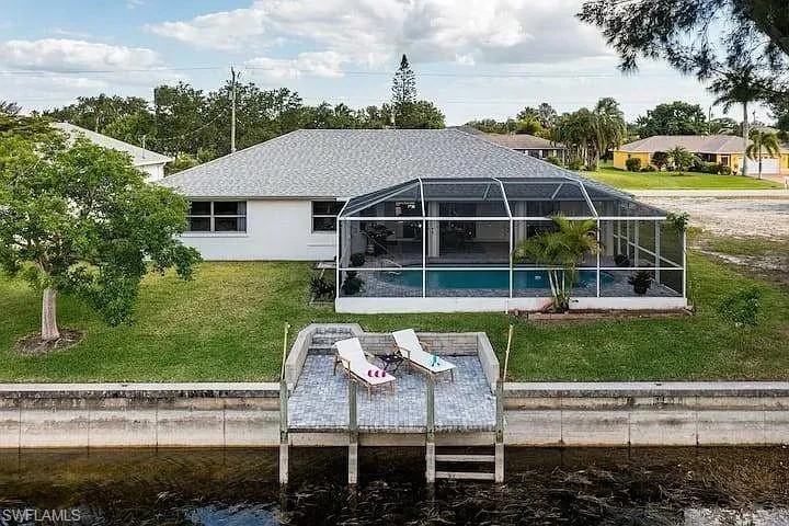 Screened-in pool enclosure, private dock, waterfront access, well-maintained lawn, and mature trees