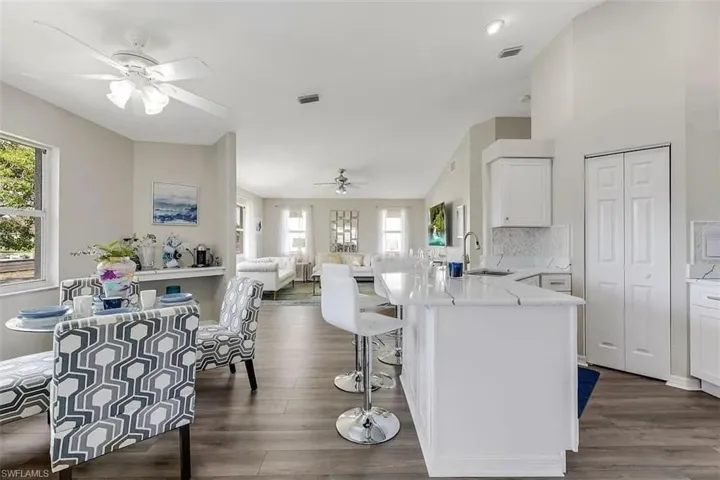 Spacious open-concept layout with wood-finish flooring, a kitchen island with stone countertops, and white cabinetry