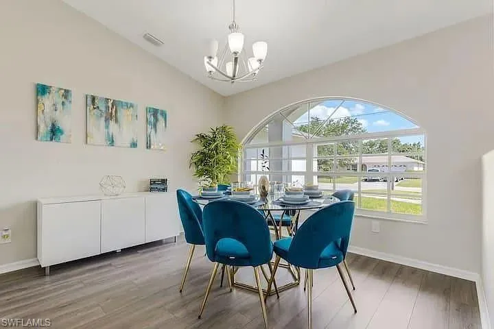 Vaulted ceiling, wood-finish flooring, half-round arched window, contemporary chandelier, and built-in white cabinetry