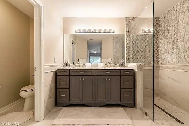Double vanity with a dark wood finish, a large mirror, and overhead lighting
