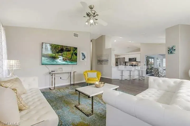 Open-concept living area featuring vaulted ceilings, wood-finish flooring, and a ceiling fan