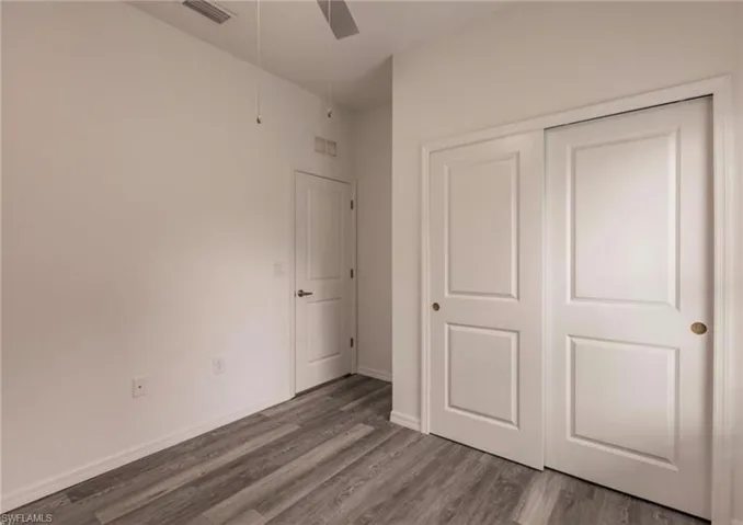 Room featuring wood-finish flooring, a ceiling fan, and white walls