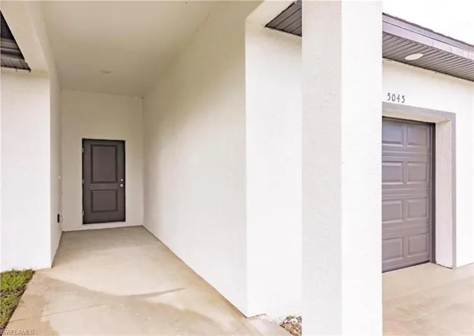 Covered entryway featuring a dark gray paneled door and overhead recessed lighting