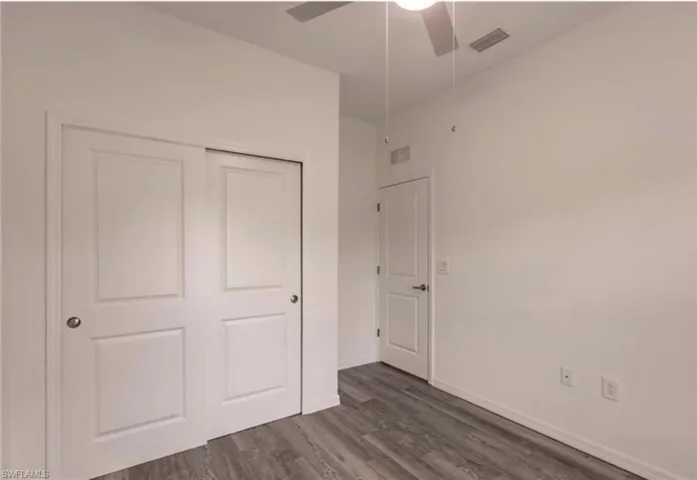 Interior space featuring wood-finish flooring, white walls, and a ceiling fan