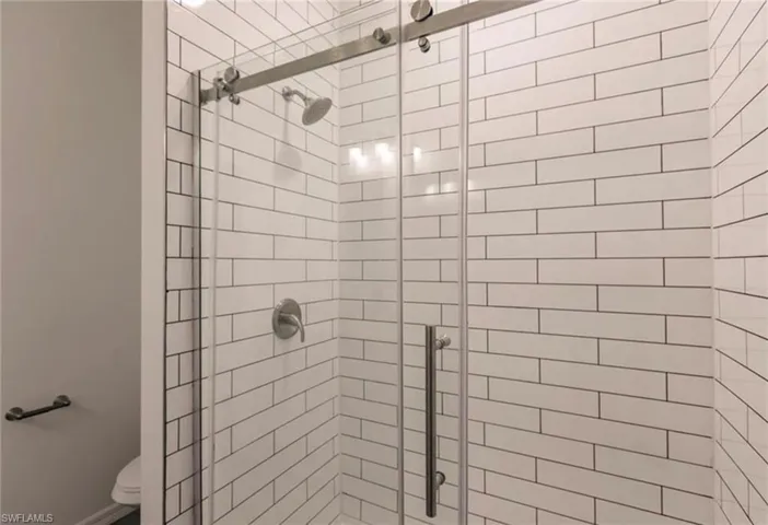 Walk-in shower featuring subway tile surround, brushed nickel hardware, and a glass sliding door