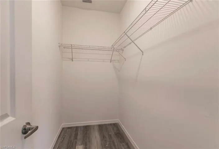 Walk-in closet featuring wire shelving, white painted walls, and wood-finish flooring