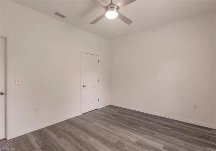 Room featuring wood-finish flooring, white baseboards, a ceiling fan with integrated lighting, and two panel doors
