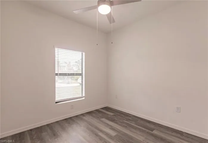Room featuring neutral wall tones, wood-finish flooring, a window with horizontal blinds, and a ceiling fan with integrated lighting