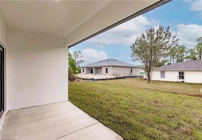 Covered concrete patio extending to a grass lawn
