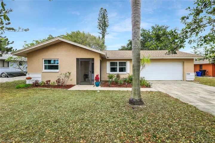 View of front of property featuring an attached garage, concrete driveway, a front lawn, and stucco siding