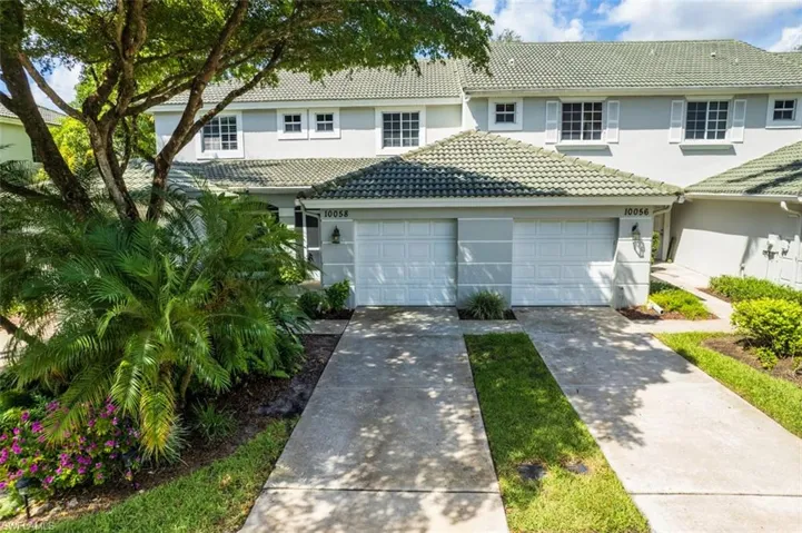 View of front of home with stucco siding, a tile roof, a garage, and driveway