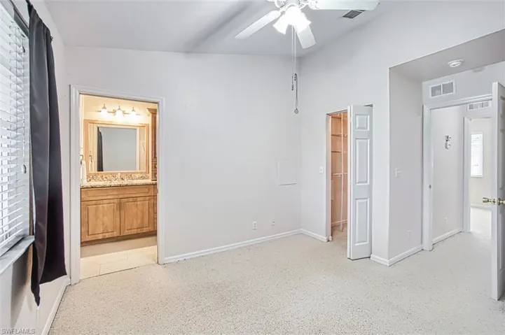 Bedroom with ensuite bath, a ceiling fan, and a spacious closet
