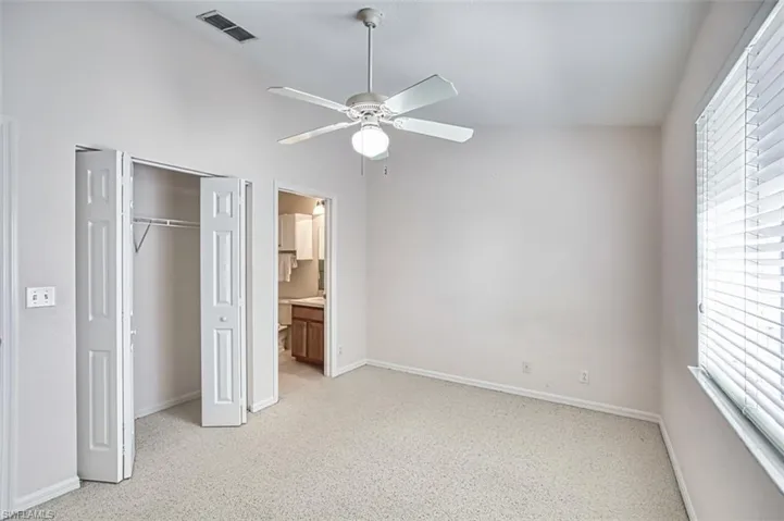 Unfurnished bedroom with a closet, ceiling fan, and ensuite bath