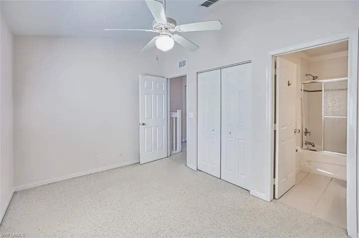 Unfurnished bedroom featuring a closet, ensuite bathroom, a ceiling fan, and a high ceiling
