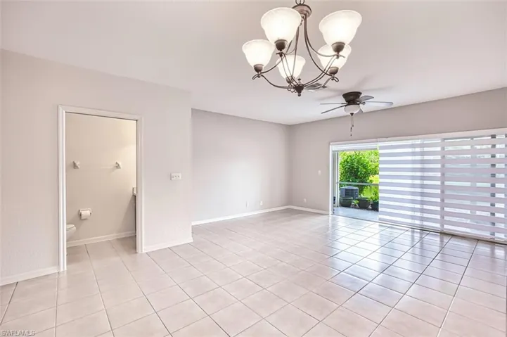 Unfurnished room featuring ceiling fan, a chandelier, light tile patterned flooring, Metro Blinds "Auror Banded Shades",  and 1/2 bath for guests