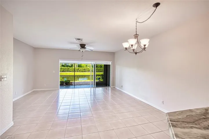 Spare room with light tile patterned floors, ceiling fan, and a chandelier