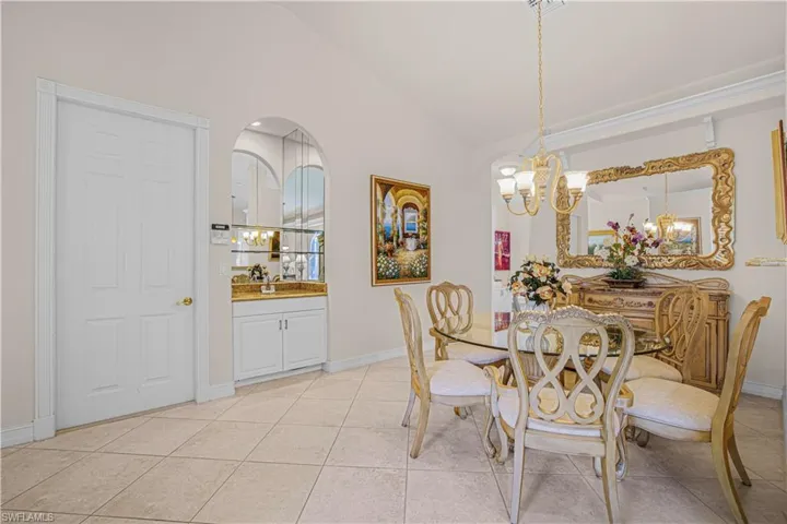 Dining room featuring a chandelier, vaulted ceiling, and light tile patterned flooring
