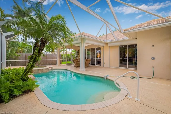 View of pool with a patio area, glass enclosure, and a pool with connected hot tub