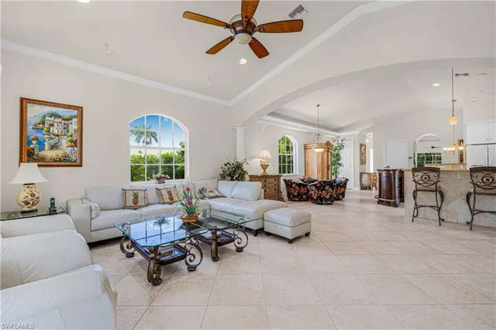 Living area featuring crown molding, arched walkways, lofted ceiling, recessed lighting, and ceiling fan