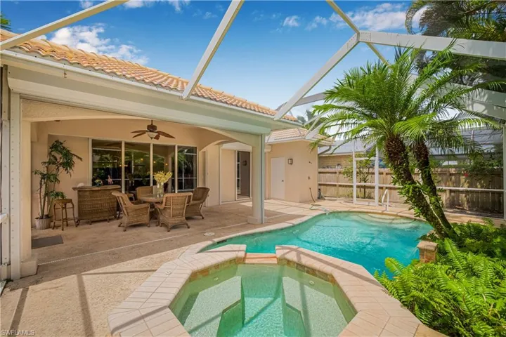 View of swimming pool with a patio area, a pool with connected hot tub, ceiling fan, and glass enclosure