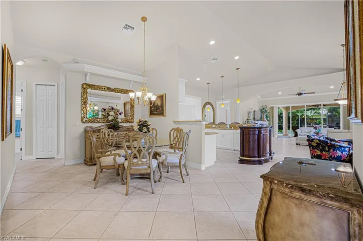 Dining space featuring a ceiling fan, light tile patterned floors, arched walkways, recessed lighting, and a chandelier