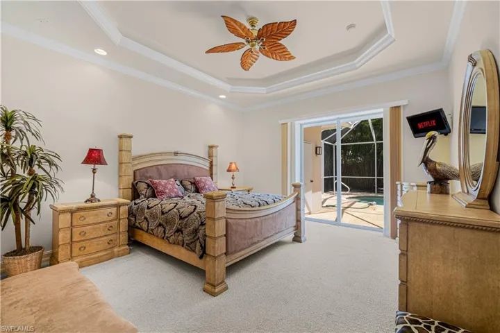 Bedroom with access to exterior, a raised ceiling, light carpet, crown molding, and ceiling fan