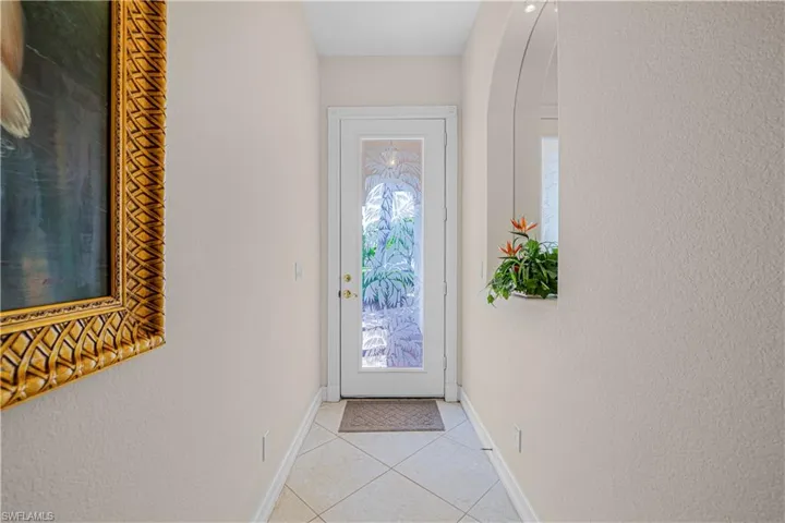 Doorway to outside featuring light tile patterned flooring and a textured wall