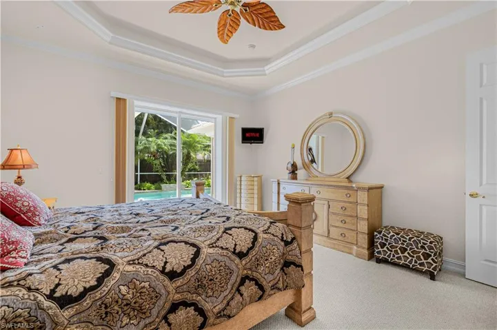 Carpeted bedroom with access to outside, crown molding, a tray ceiling, and a ceiling fan