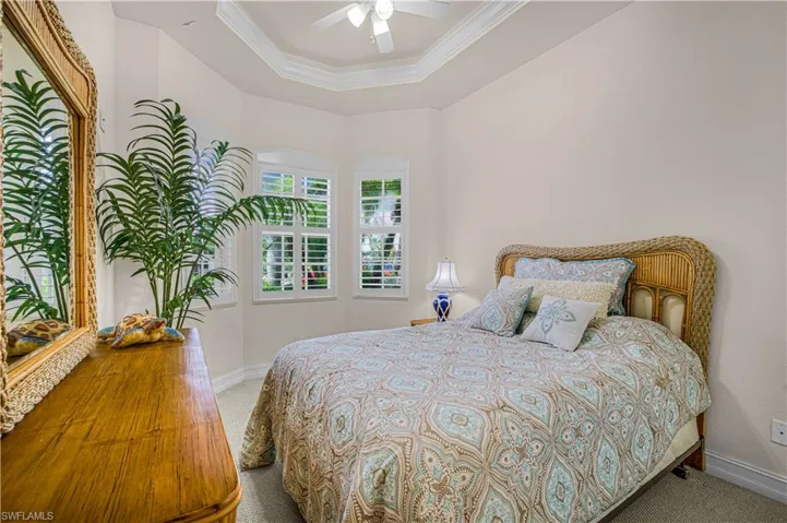 Carpeted bedroom with ornamental molding, a raised ceiling, and a ceiling fan