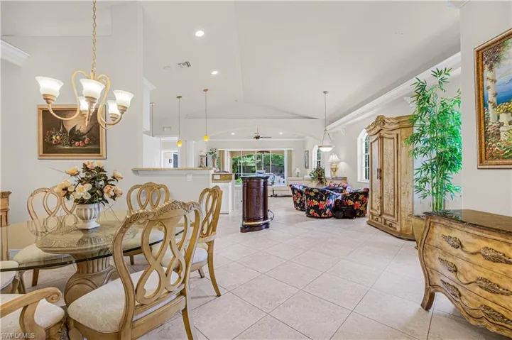 Dining area featuring vaulted ceiling, light tile patterned floors, crown molding, recessed lighting, and a ceiling fan