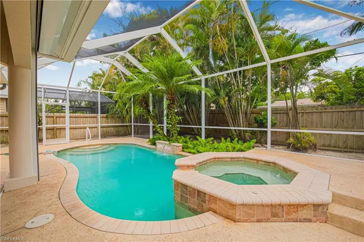 View of swimming pool with a fenced backyard, glass enclosure, an in-ground hot tub, and a patio area