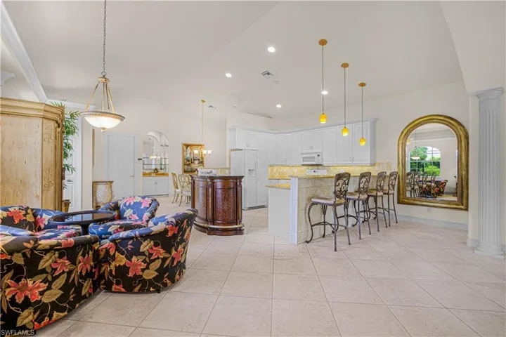 Living room with lofted ceiling, light tile patterned floors, decorative columns, and recessed lighting